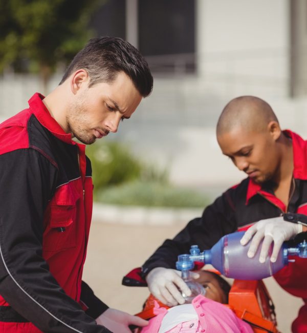 paramedic giving oxygen to injured girl at accident spot